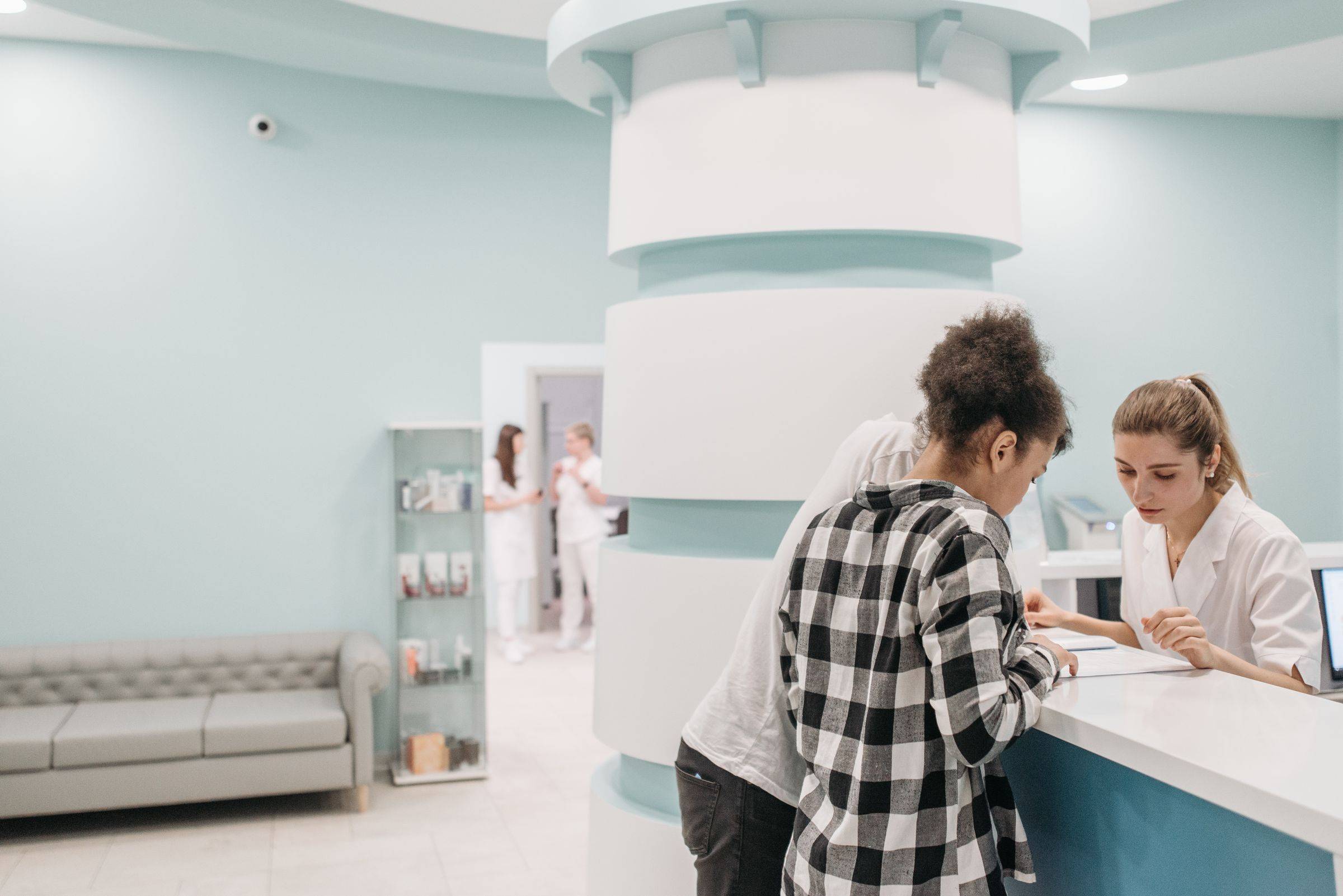 A patient checks in at the front desk of a bright, small clinic.